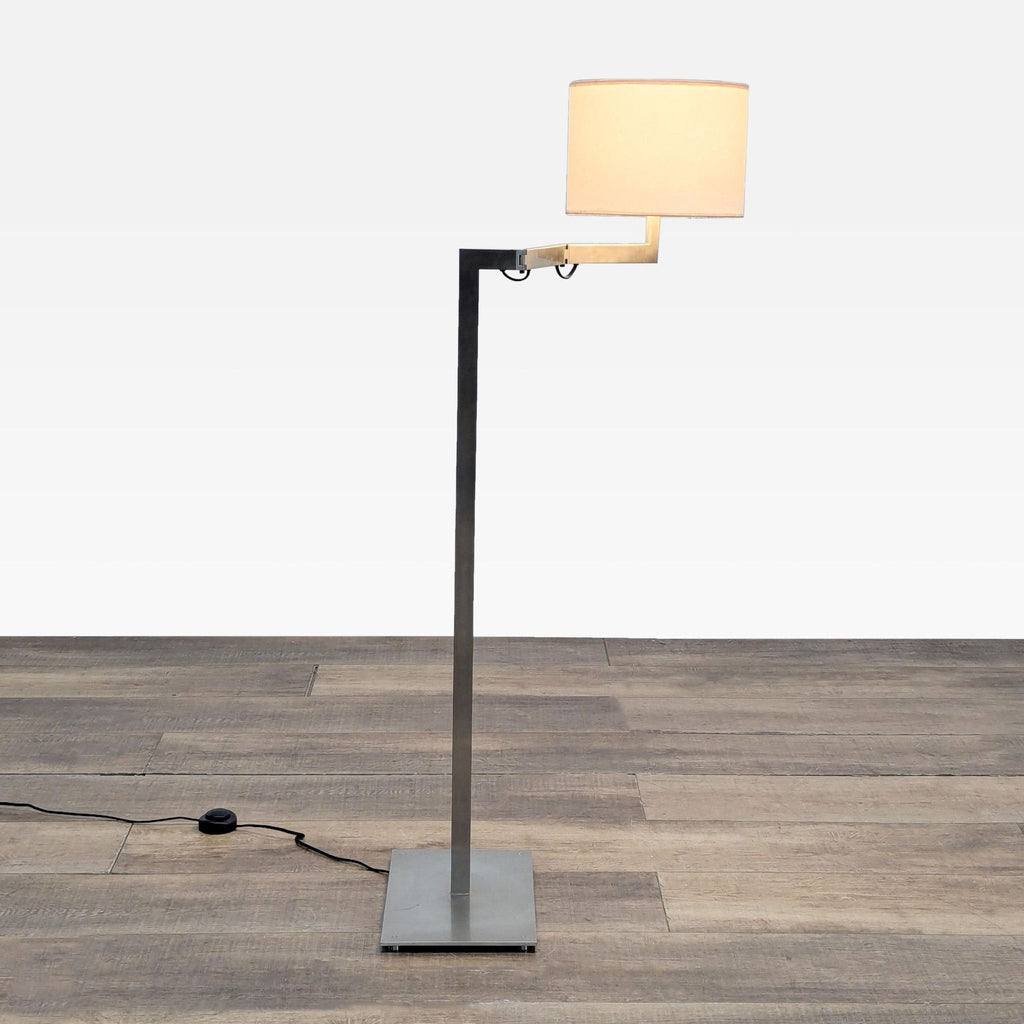 1. Reperch floor lamp with sleek metal stand, adjustable arm, and cylindrical fabric lampshade on wood floor.