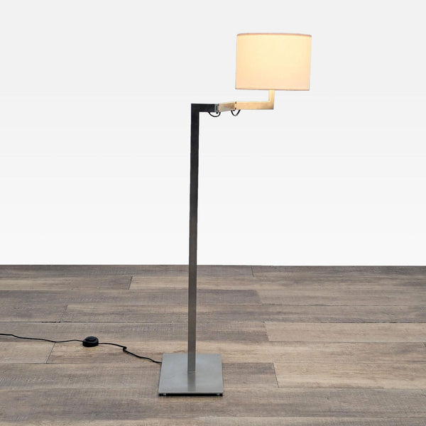 1. Reperch floor lamp with sleek metal stand, adjustable arm, and cylindrical fabric lampshade on wood floor.