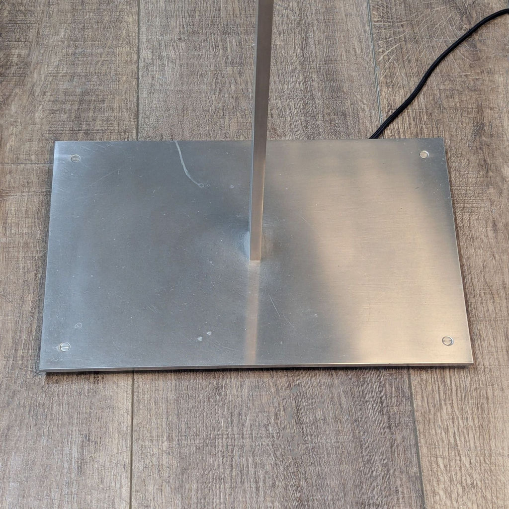 3. Base of Reperch lighting fixture showing a square metal support on wooden flooring with visible power cord.