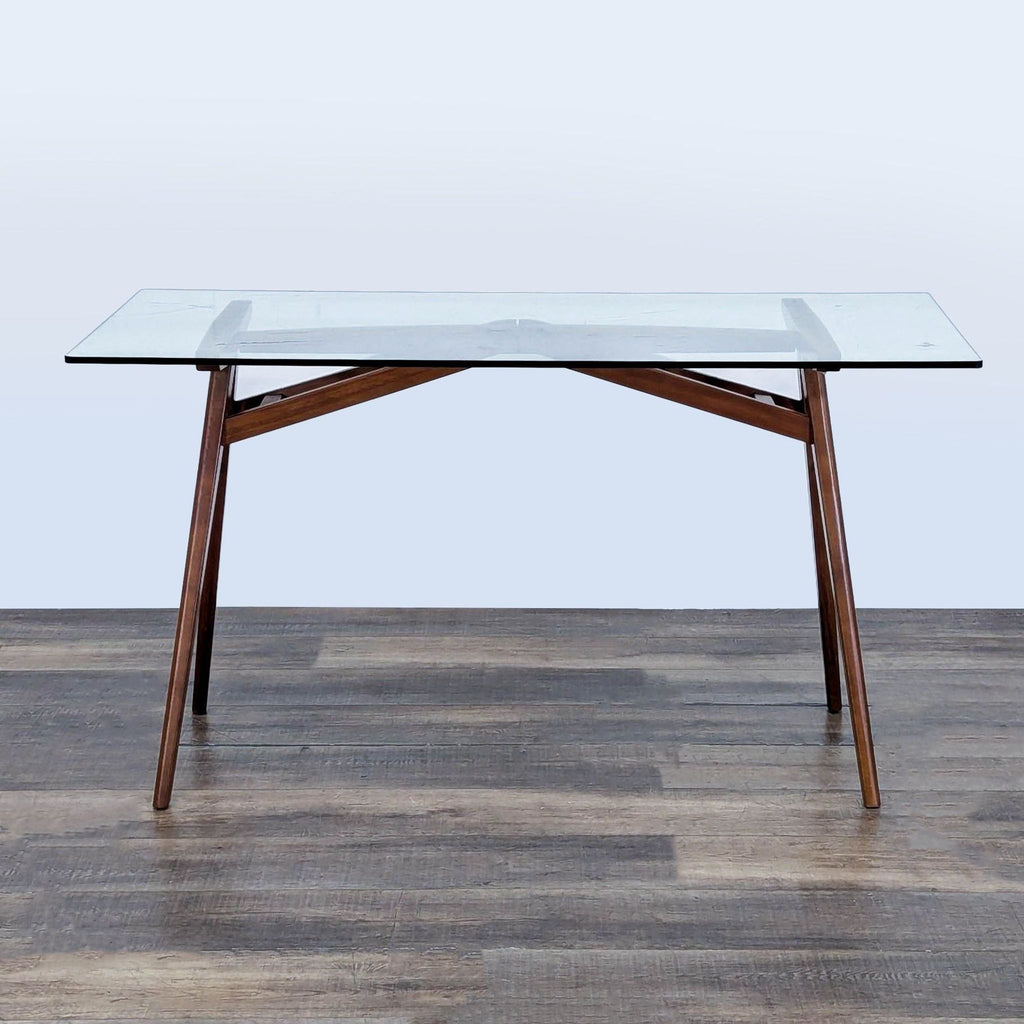 3. Modern West Elm desk with clear glass top and angled solid wood base, suited for home or office workspace.
