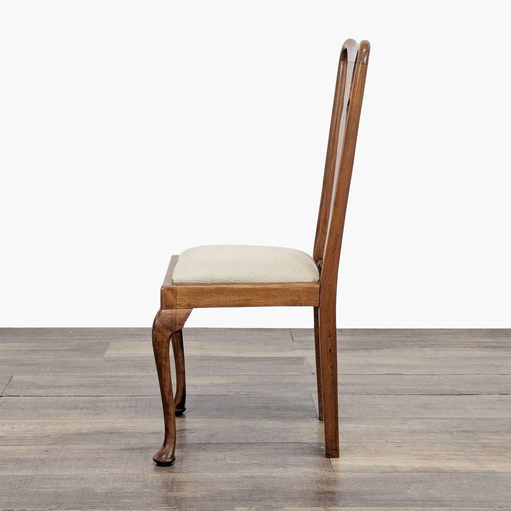 Side profile of a Reperch dining chair with curved backrest and wooden legs, upholstered in light fabric.