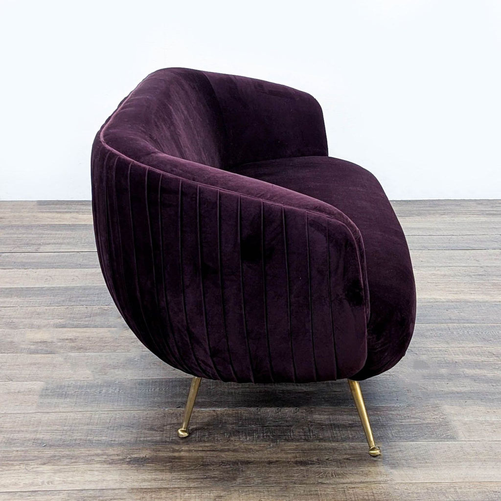 2. Side angle of Reperch 3-seat sofa showing pleated velvet and rounded profile with gold legs.  