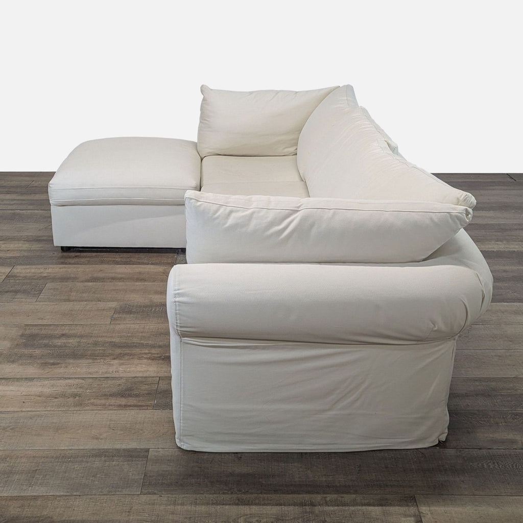 Side angle of Pottery Barn cream twill sectional sofa with a chaise and plush rolled arm design.