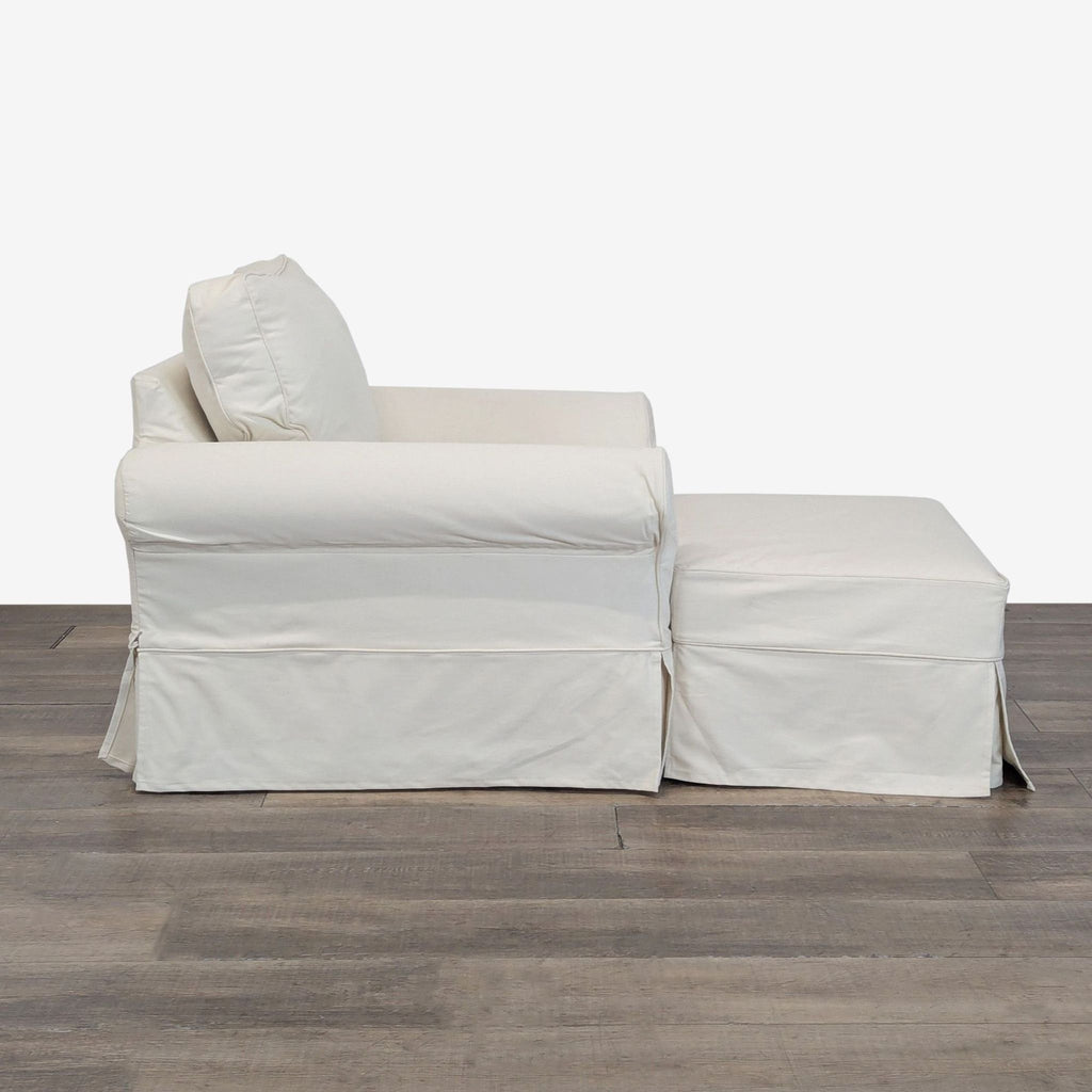 Side view of a Pottery Barn cream twill slipcovered lounge chair and matching ottoman on wood flooring.  