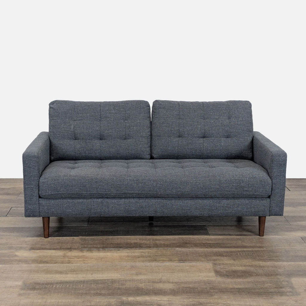 Reperch Loveseat with tufted cushions and tapered wood feet, front view on wood floor.  