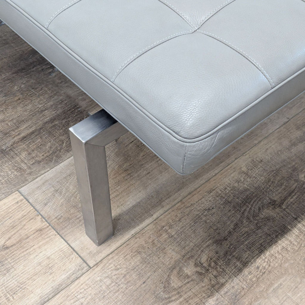 2. Close-up of the HD Buttercup bench’s metal leg and textured grey leather cushion with visible stitching.