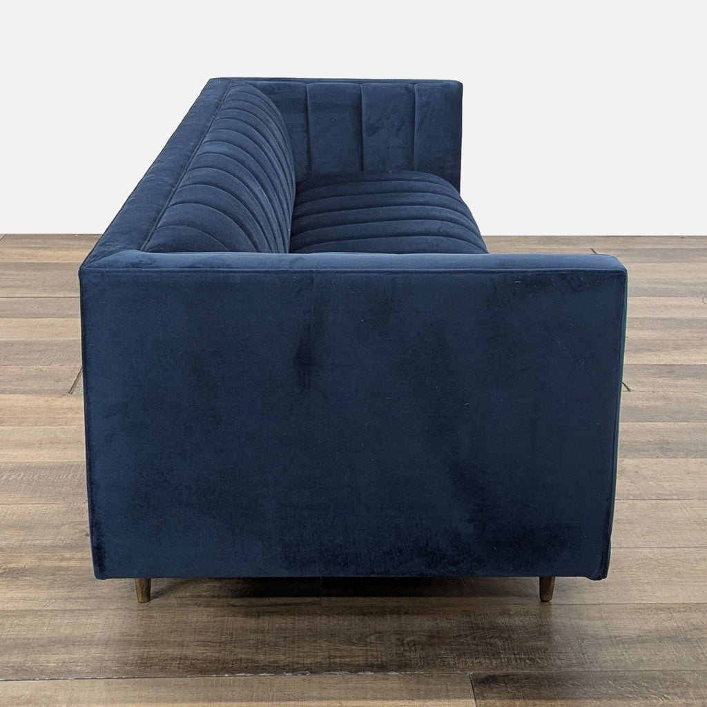 2. Side view of Four Hands navy 3-seat sofa with classic lines, plush channeling, and sleek wooden tapered legs.