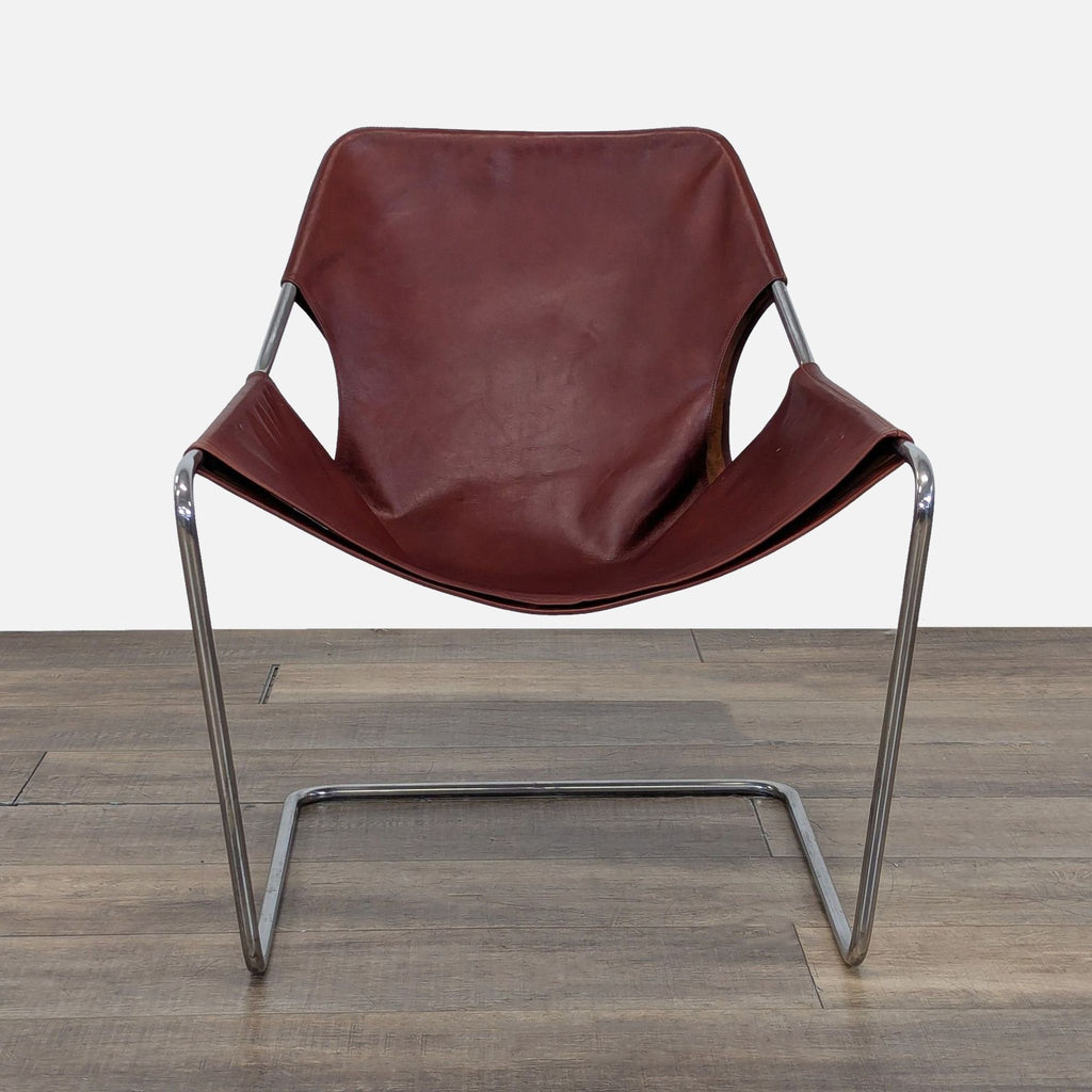 Front view of a Reperch Paulistano Armchair with a brown leather seat and a sleek, continuous steel frame.  