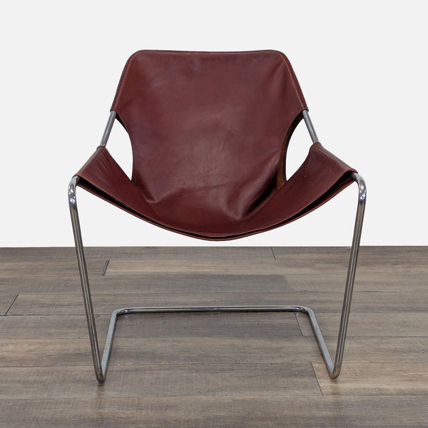 1. Front view of the Paulistano Armchair, featuring a brown leather seat and continuous polished steel frame.  