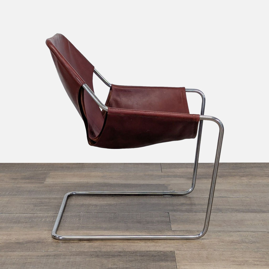 2. Side view of the Design Within Reach Paulistano Lounge Armchair, showing its sleek steel construction and leather sling.  