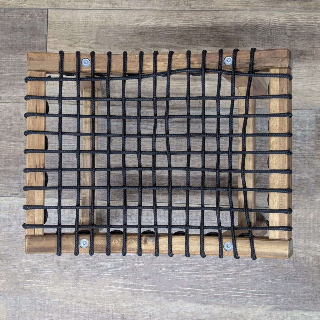 Top-down view of a Reperch stool, highlighting its wooden frame and black crisscross rope seat.