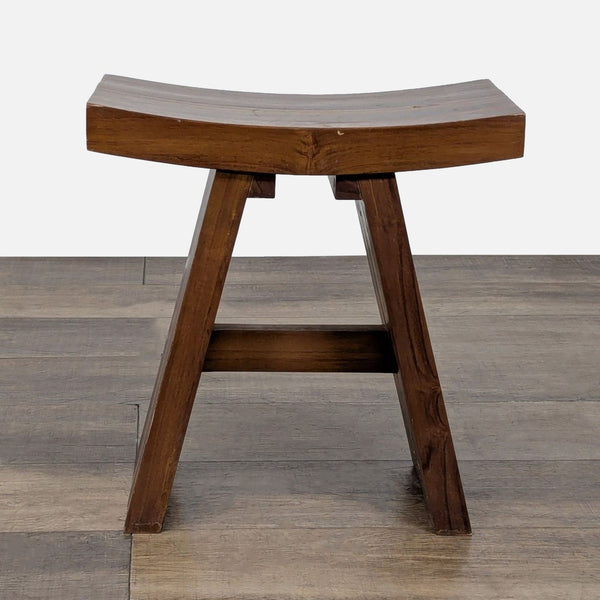 1. Redmon wooden stool with a curved seat and angled legs, shown on a wooden floor.