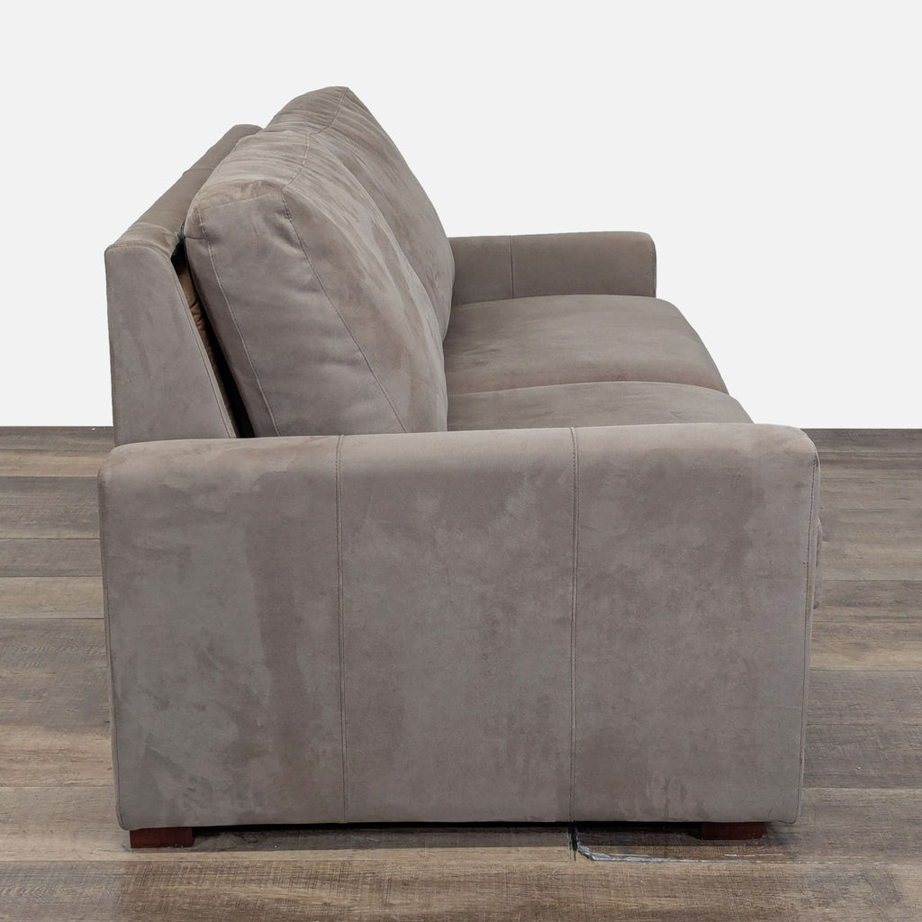 2. Side profile of a Room & Board suede sleeper sofa showing plush cushions and boxy armrest design.