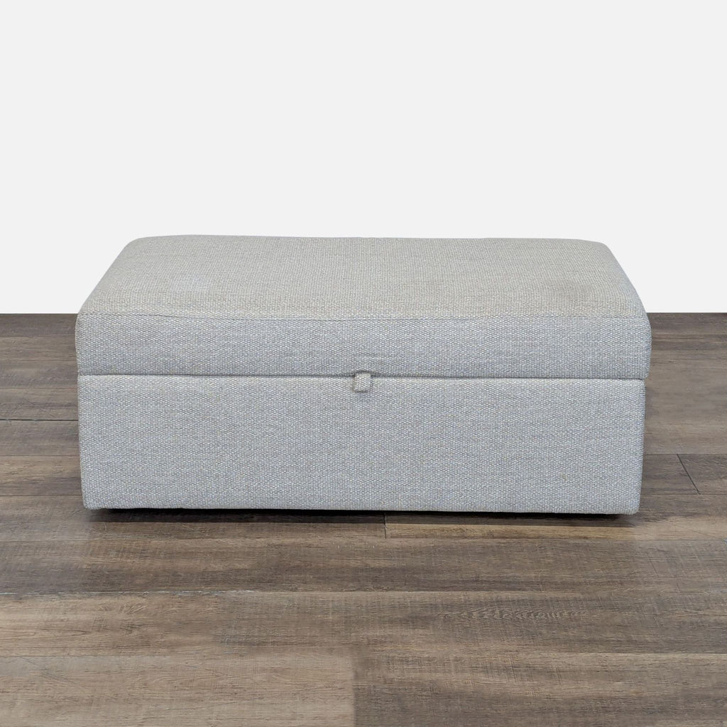 1. Rectangular Pottery Barn ottoman in light gray upholstery, closed, on dark wood flooring.