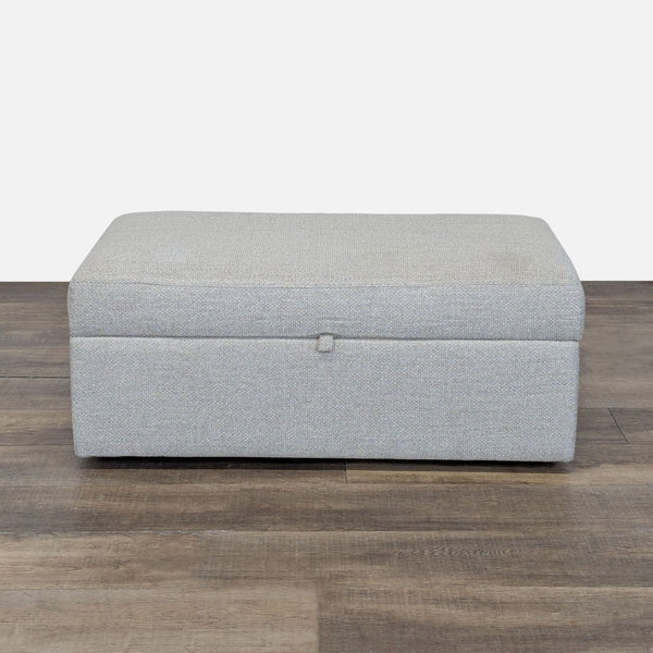 1. Rectangular Pottery Barn ottoman in light gray upholstery, closed, on dark wood flooring.