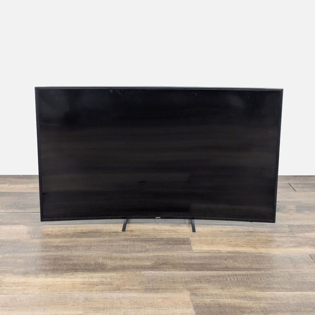 1. Front view of a 55-inch Samsung curved Smart TV with a sleek black screen, standing on a wooden floor.