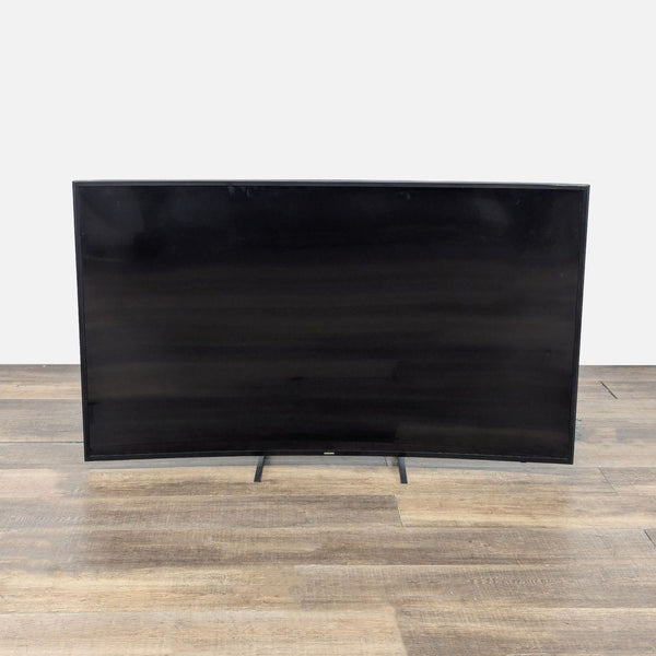 1. Front view of a 55-inch Samsung curved Smart TV with a sleek black screen, standing on a wooden floor.