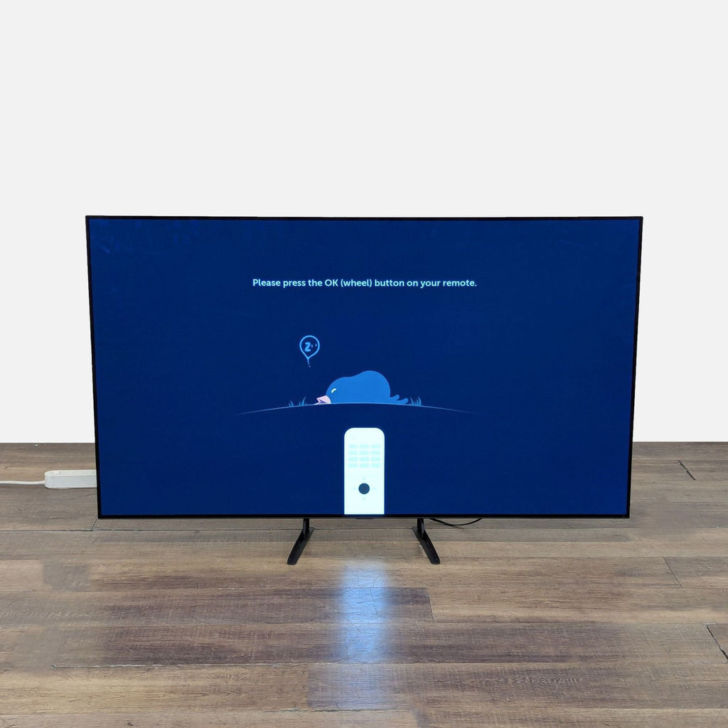 2. LG OLED TV displaying a setup screen instructing to press the OK button on the remote, TV on a stand.  