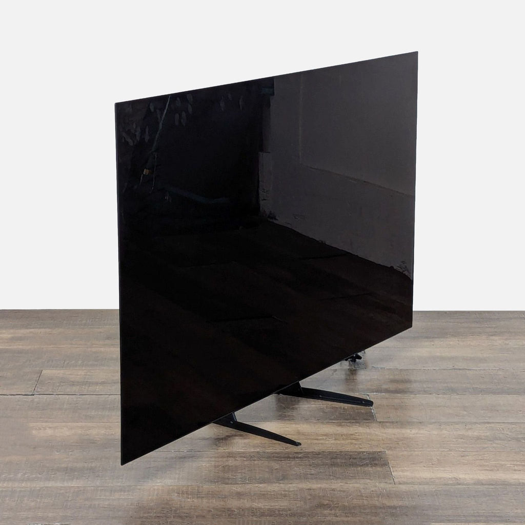 3. Angled side view of the 65-inch LG OLED TV showing its thin profile and modern design on wooden floor.