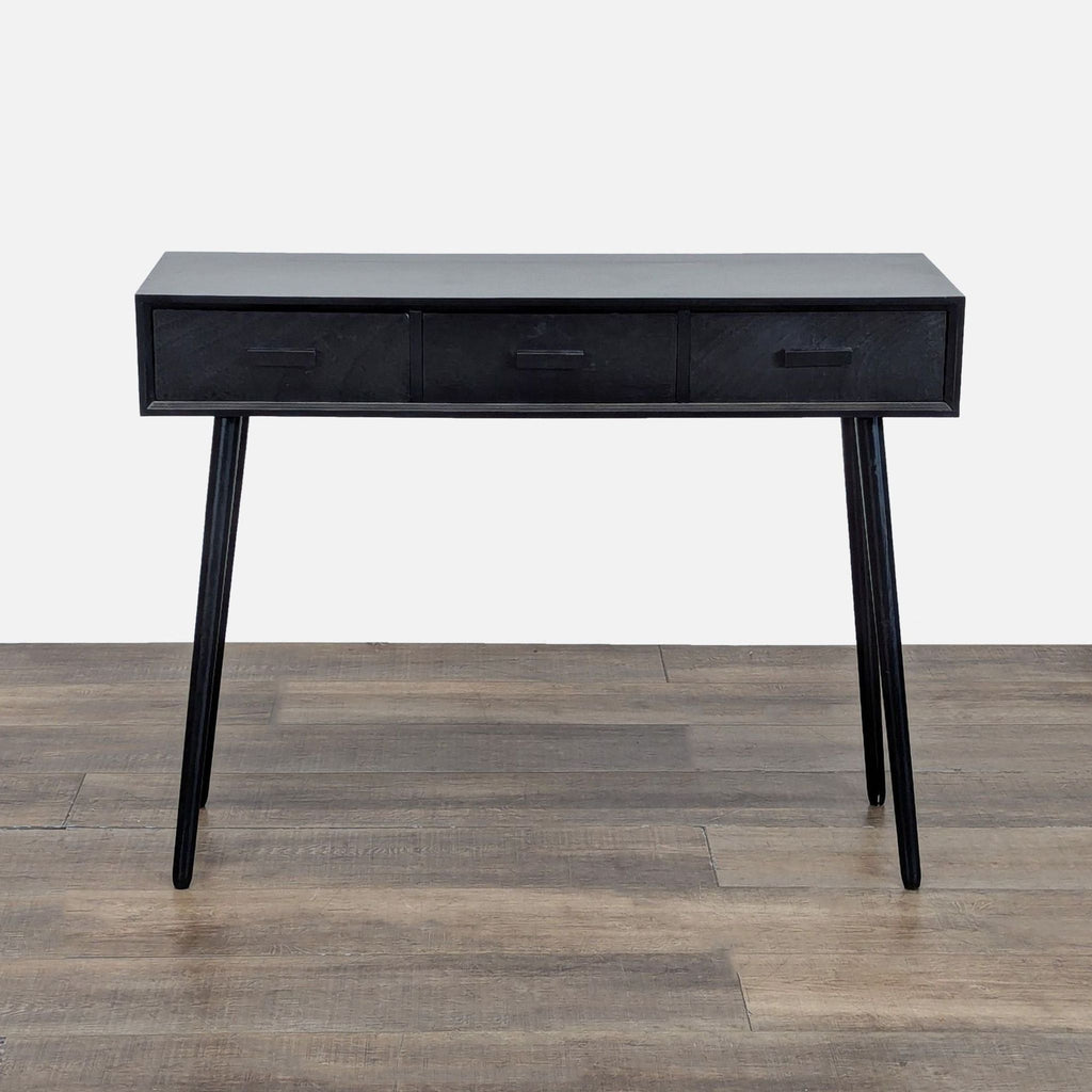 1. Black Reperch side and console table with three drawers and angled legs, shown on a wooden floor.