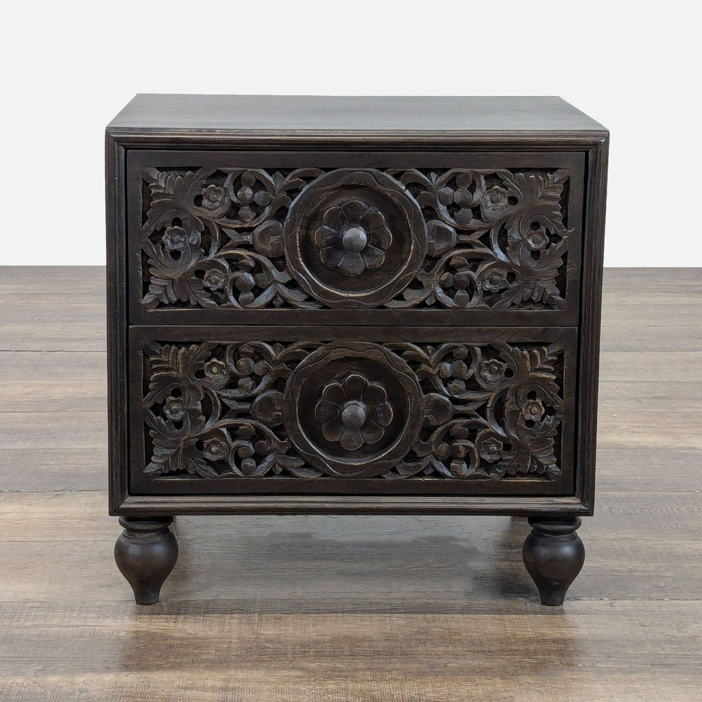 Ornate dark wood Reperch end table with two floral-carved drawers, shown on a wooden floor.