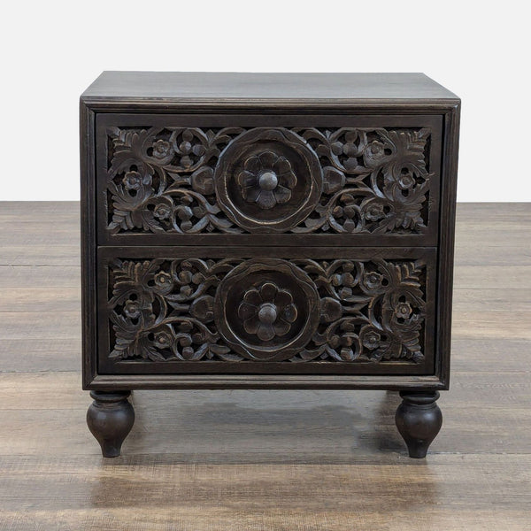 Ornate dark wood Reperch end table with two floral-carved drawers, shown on a wooden floor.