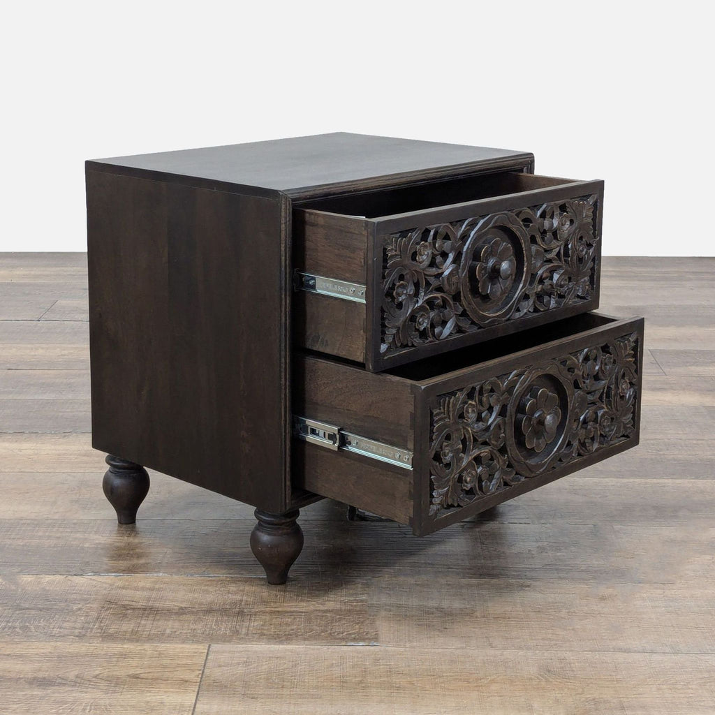Side view of a Reperch end table, featuring two open carved drawers with floral patterns and wooden legs.