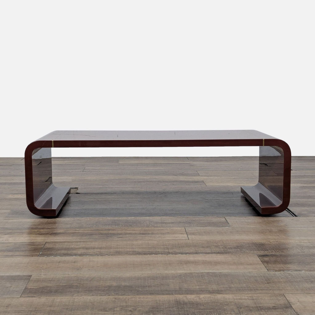Arteriors coffee table in paprika lacquer with thin antique brass inlay and modern angular legs, front view.