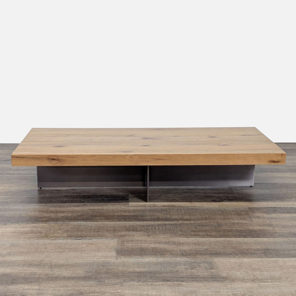 Wide rectangular wooden coffee table by Reperch with metal base, shown on a wood floor against white background.  