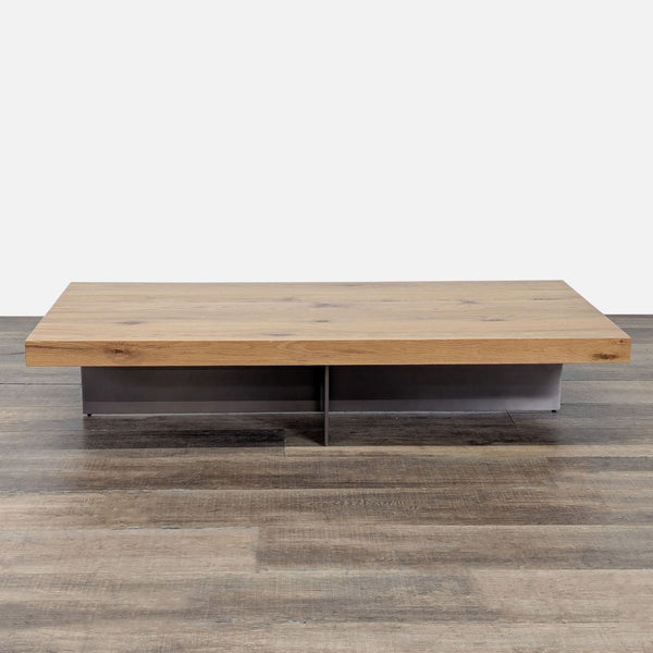 Wide rectangular wooden coffee table by Reperch with metal base, shown on a wood floor against white background.  