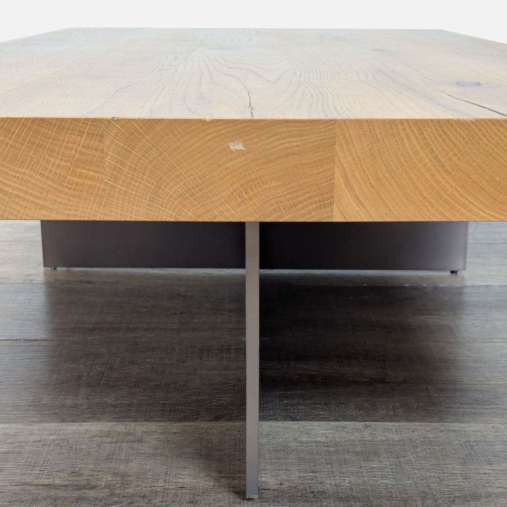 Close-up side view of Reperch coffee table, highlighting thick wooden top and minimal metal cross base.  