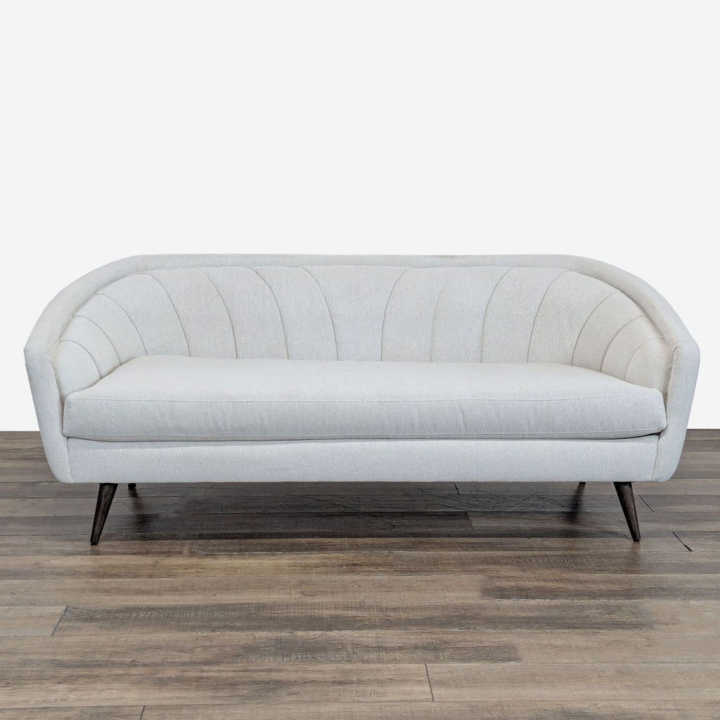 1. Four Hands 3-seat sofa with curved lines and channel tufting, upholstered in light fabric, front view.