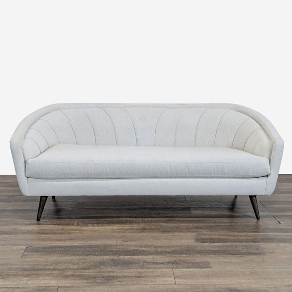 1. Four Hands 3-seat sofa with curved lines and channel tufting, upholstered in light fabric, front view.