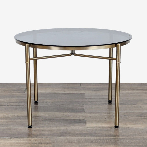 Round Reperch dining table with a metal base and black tabletop, shown on wooden flooring.  
