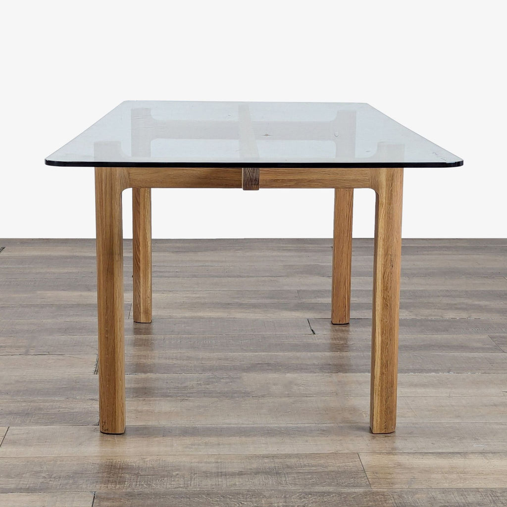 2. Side view of an EQ3 dining table featuring a wooden oak base and a transparent glass top.