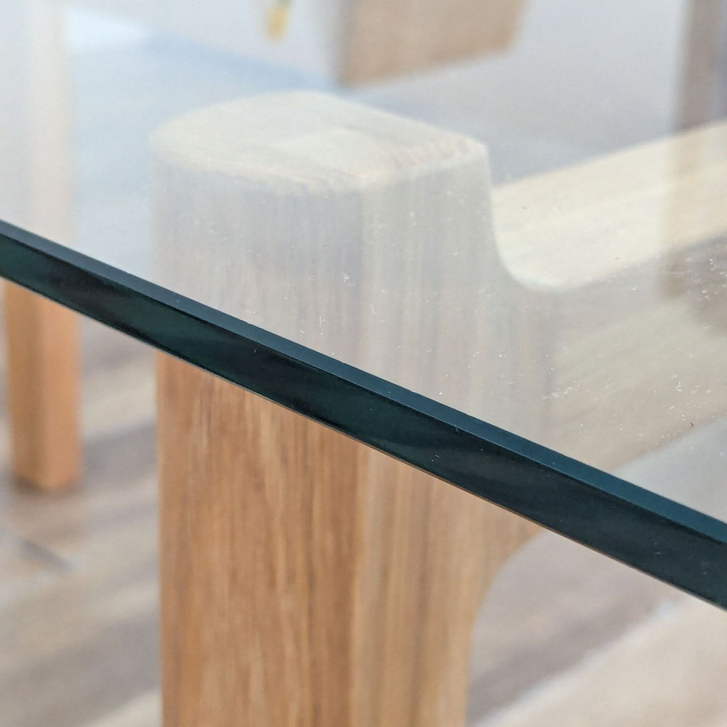 3. Close-up of the EQ3 dining table showing the glass top and natural oak base details.