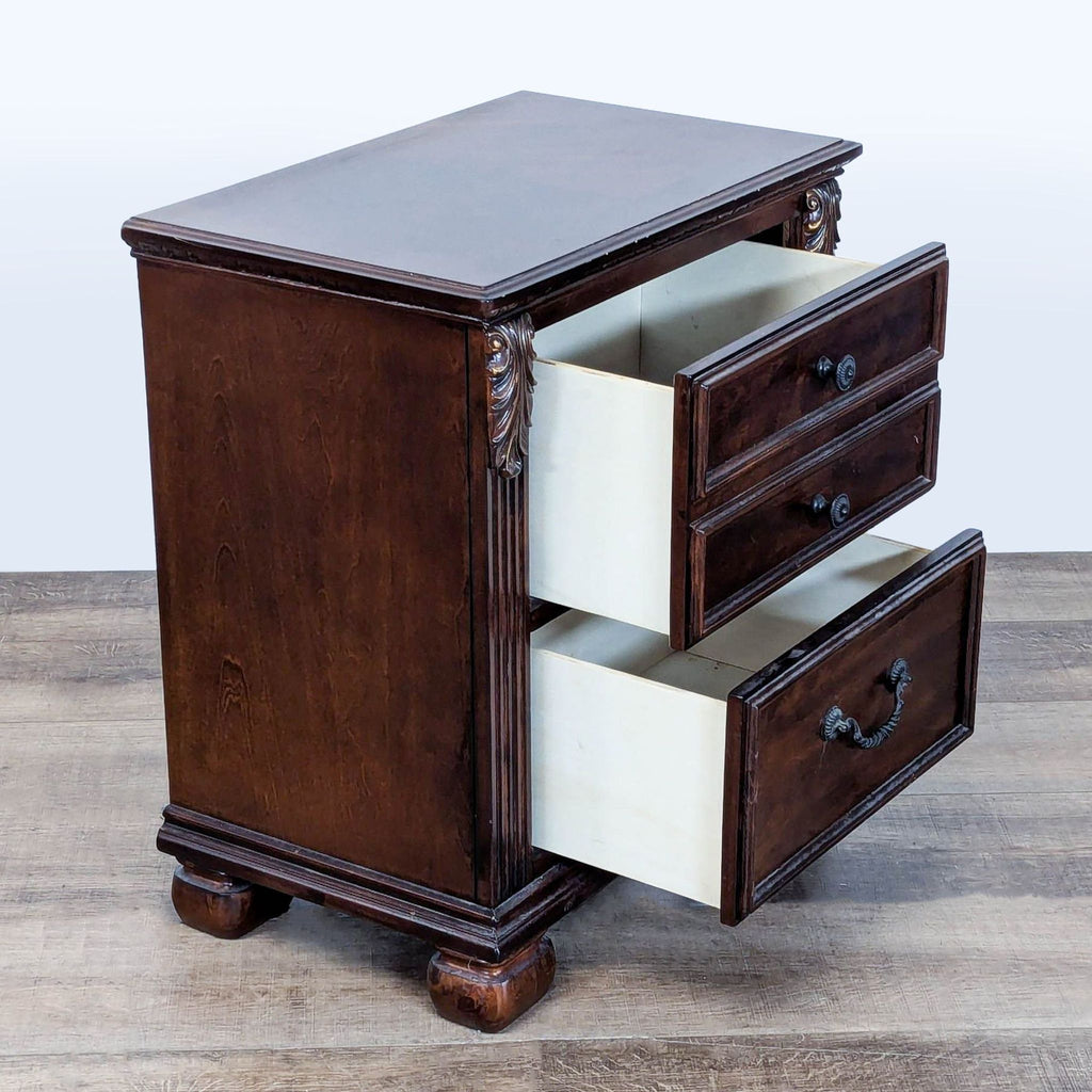Ashley Furniture Leahlyn end table showing two open drawers, ornate leaf corbels, and fluted pilasters.