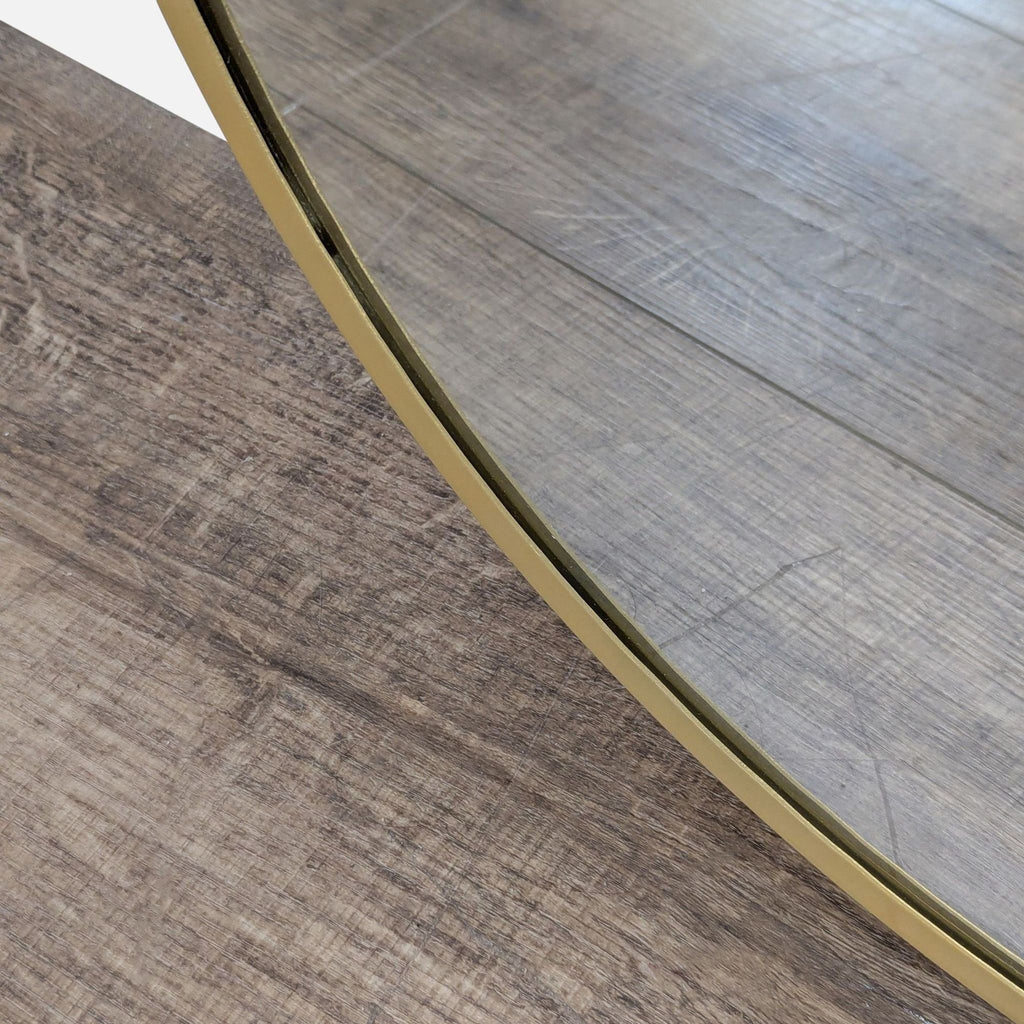 2. Close-up of the Reperch mirror's gold frame showing its sleek edge against wood flooring.