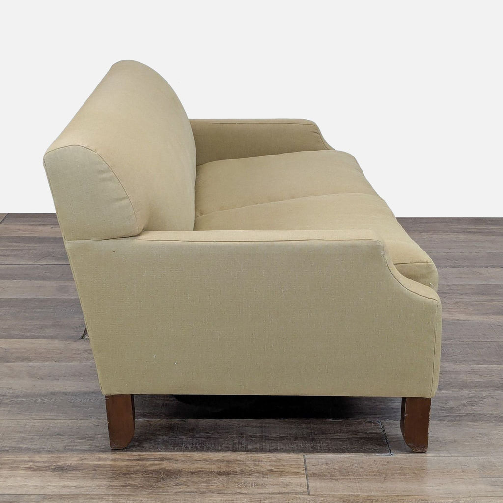 2. Side view of a Cisco Brothers three-seat sofa, showing sloped arms and wooden tapered legs on a wood floor.
