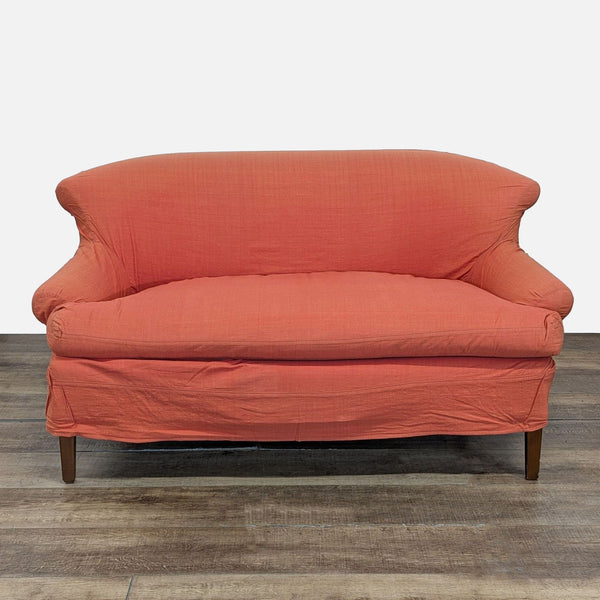 1. Front view of a coral Chippendale style loveseat with slipcover, by Cisco Home, on wooden legs.  