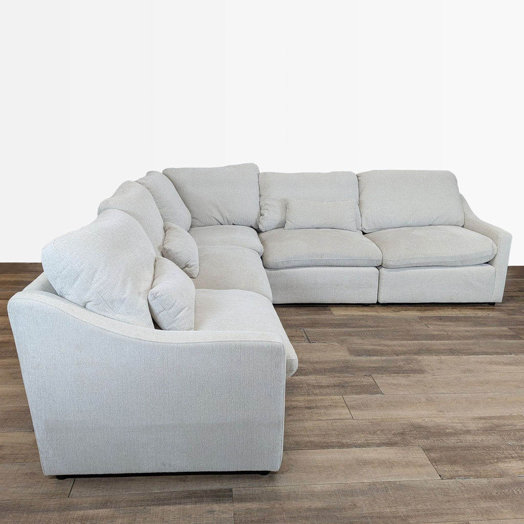 1. Living Spaces sectional sofa with cream upholstery and slim track arms, displayed in a corner setup.