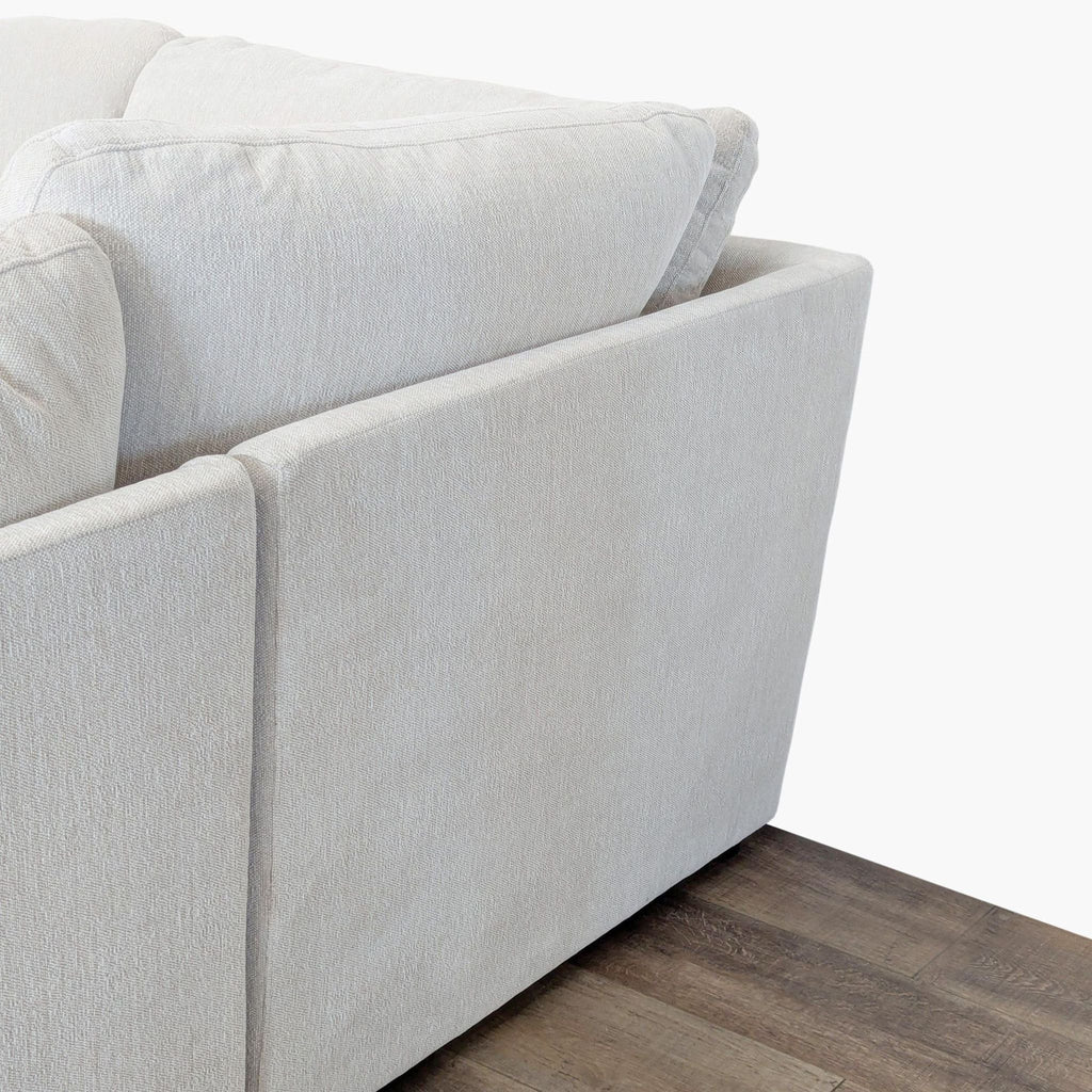 3. Detail of the back and arm of a Living Spaces cream sectional, showing its slim track design.