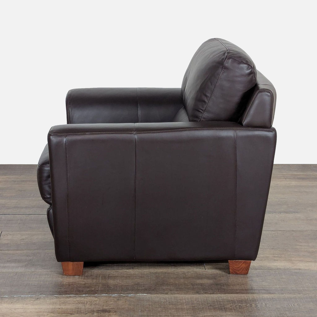 2. Side angle of a dark leather Ikea lounge chair in the Lounge category, showcasing padded arm and wooden legs.