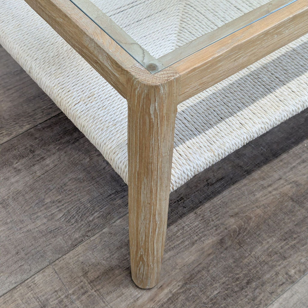Close-up of corner detail on Reperch coffee table, highlighting wood grain, glass surface, and woven shelf.