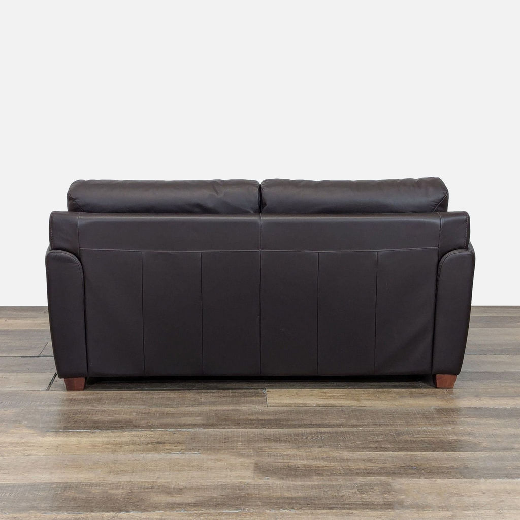 Back view of an Ikea 3-seat sofa showing its leather upholstery and simple, modern design with wood feet.