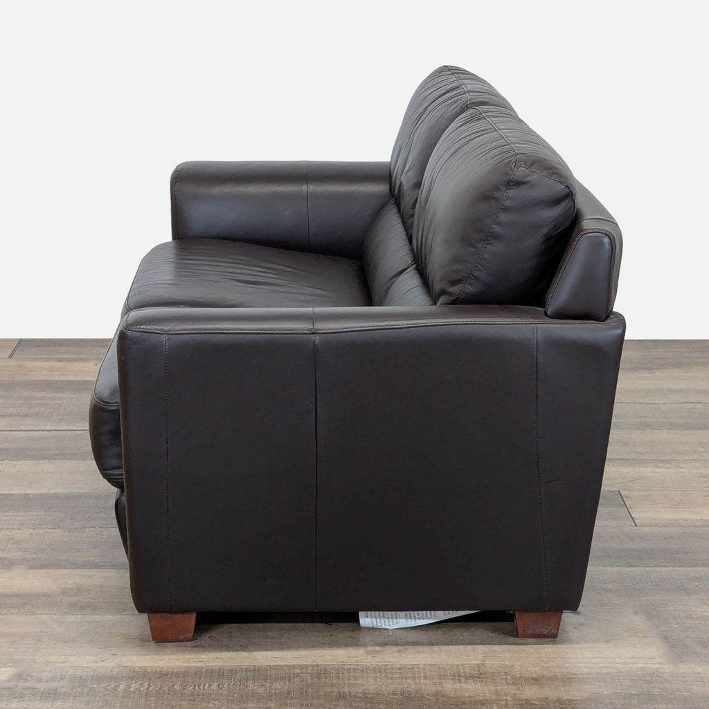 Side view of an Ikea 3-seat leather sofa featuring smooth arms and tapered wooden block feet.