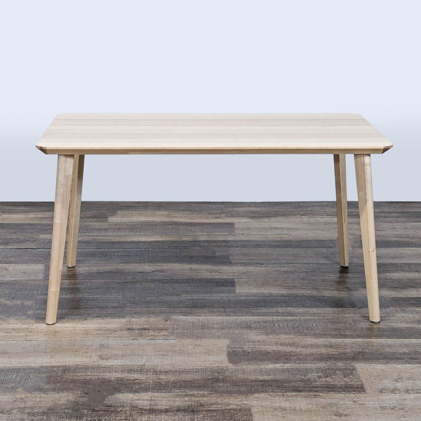 Rectangular Ikea dining table with ash veneer finish, simple design and four tapered legs, on wooden floor.  