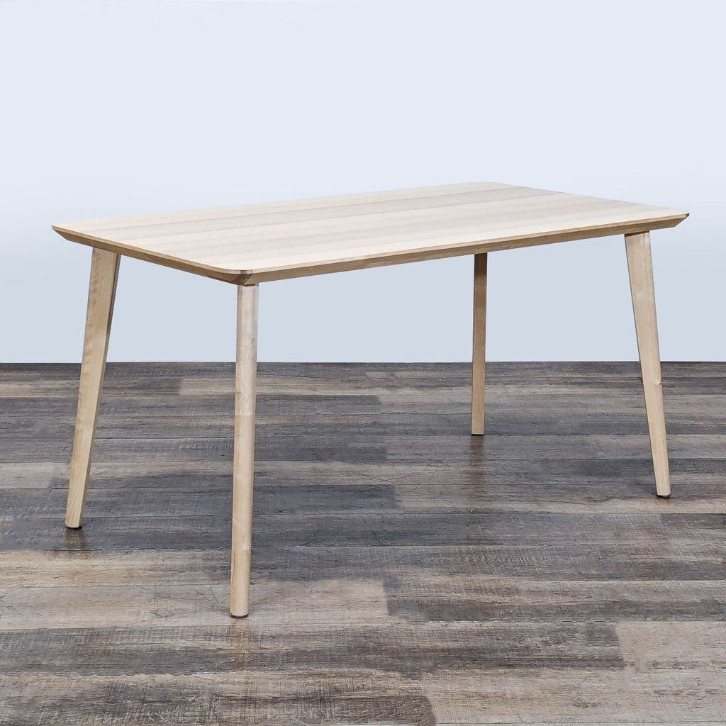 Light ash veneer Ikea dining table, rectangular top, minimalist style, with four angled legs, on rustic flooring.  