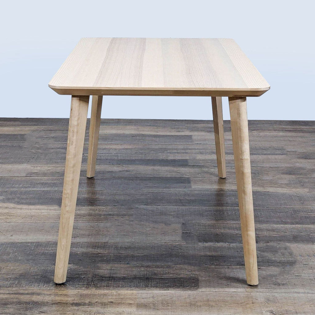 Ikea dining table in ash veneer, rectangular with rounded corners, sturdy skinny legs, pictured from the short end.