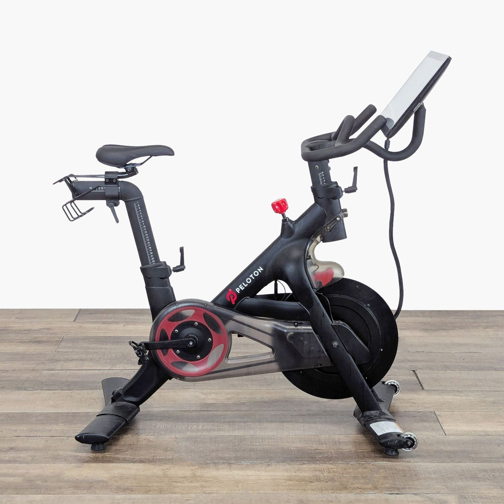 2. Side profile of a Peloton branded exercise bike, gym equipment featuring an integrated digital screen.